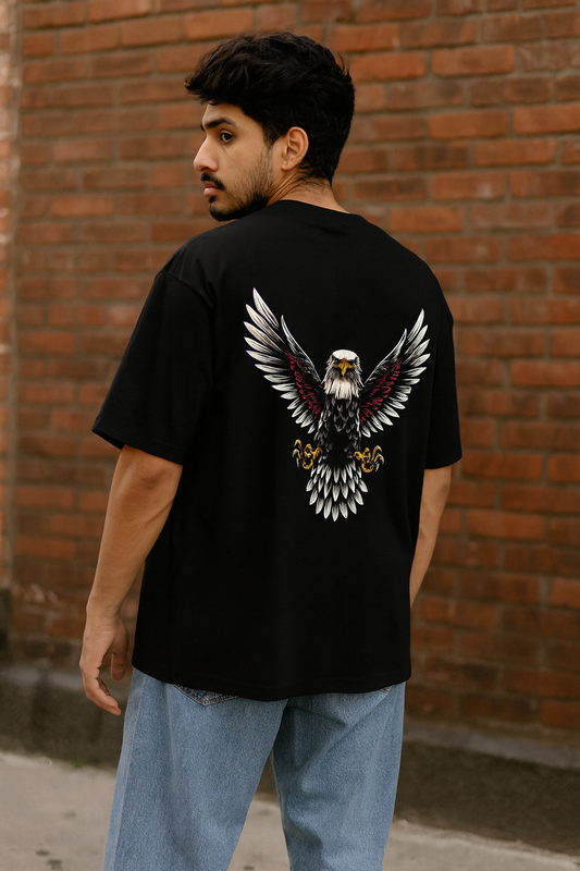 Person wearing a black t-shirt with an eagle design on the back against a brick wall