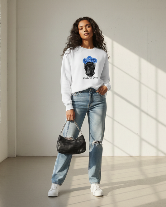 Woman wearing a skullflower white sweatshirt with a graphic design and blue jeans, standing in a well-lit room.